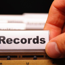 photo of a persons hand holding a file folder labeled records