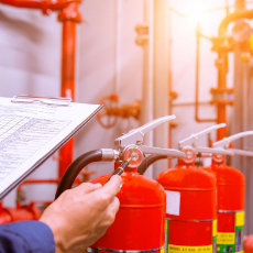 fire extinguishers being inspected by a person holding a clipboard