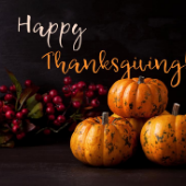 Black background with orange pumpkins and purple grapes and reads Happy Thanksgiving