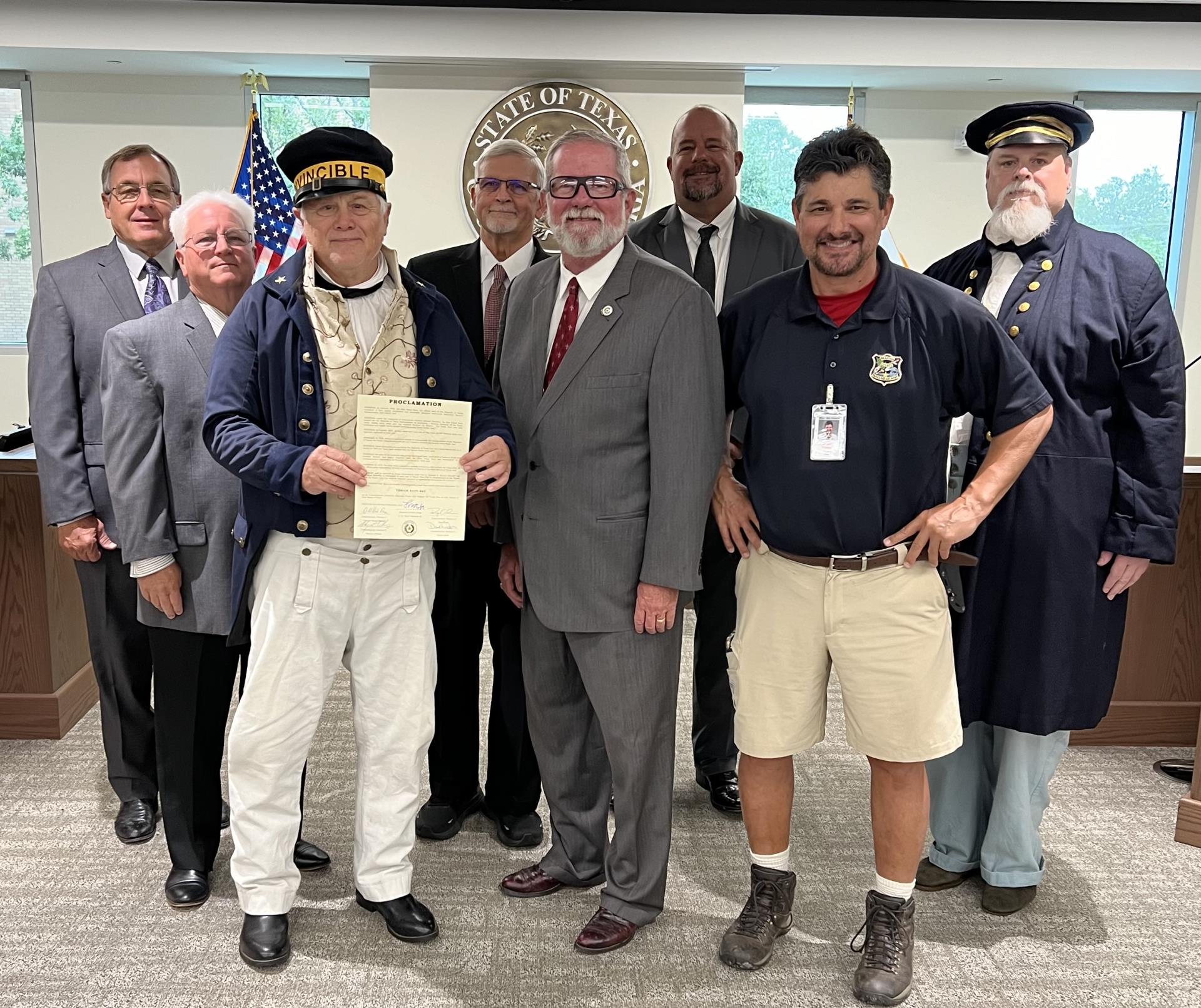 Commissioners of Brazoria County and others posing for a picture of the paper proclamation for Texian Navy Day